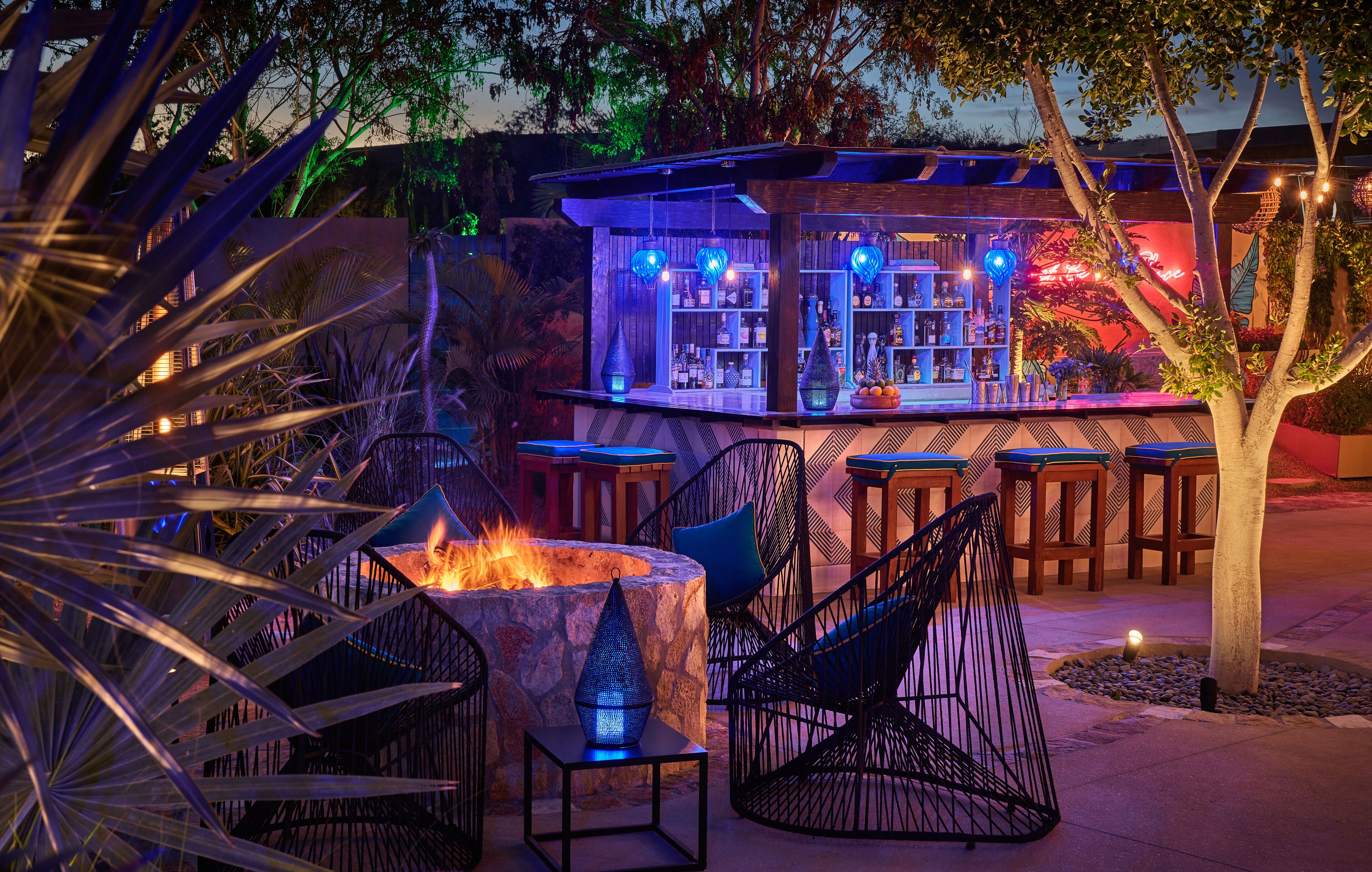 An outdoor bar area with a fire feature, seating, and a bar stocked with bottles.