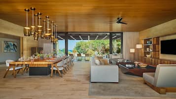 A spacious living area with a wooden ceiling, a dining table set for six, and a large sofa.