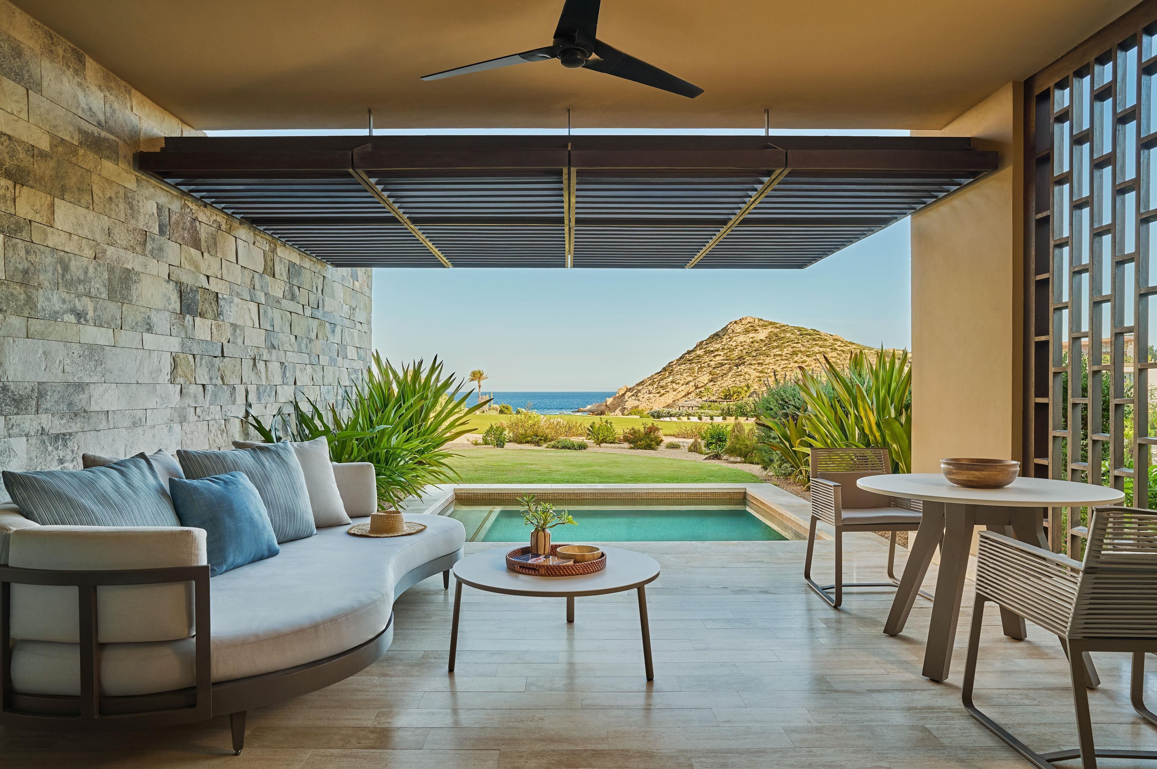 A modern outdoor living area with a pool, a sofa, and a table.