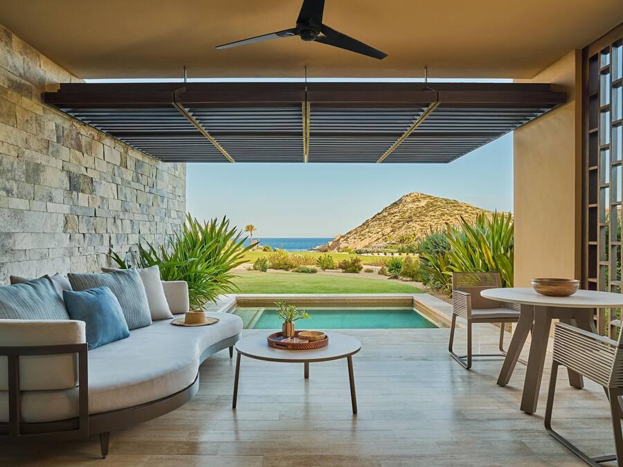 A modern outdoor living area with a pool, a sofa, and a table.