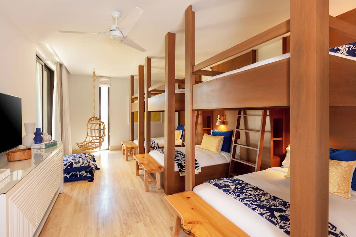 A hotel room with bunk beds, a flat-screen TV, wooden furniture, and a ceiling fan.