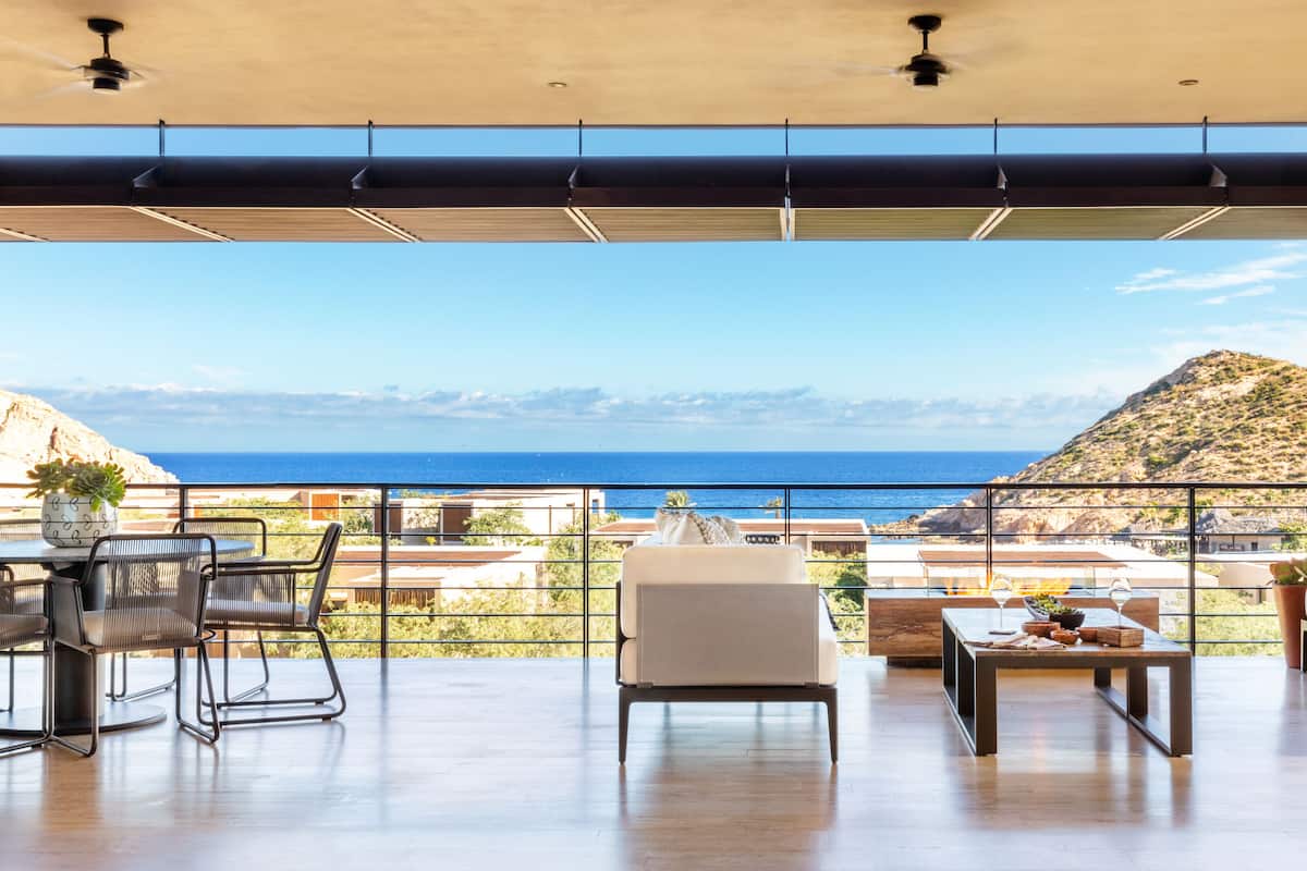A spacious balcony with a view of the sea, furnished with a table, chairs, and a sofa.