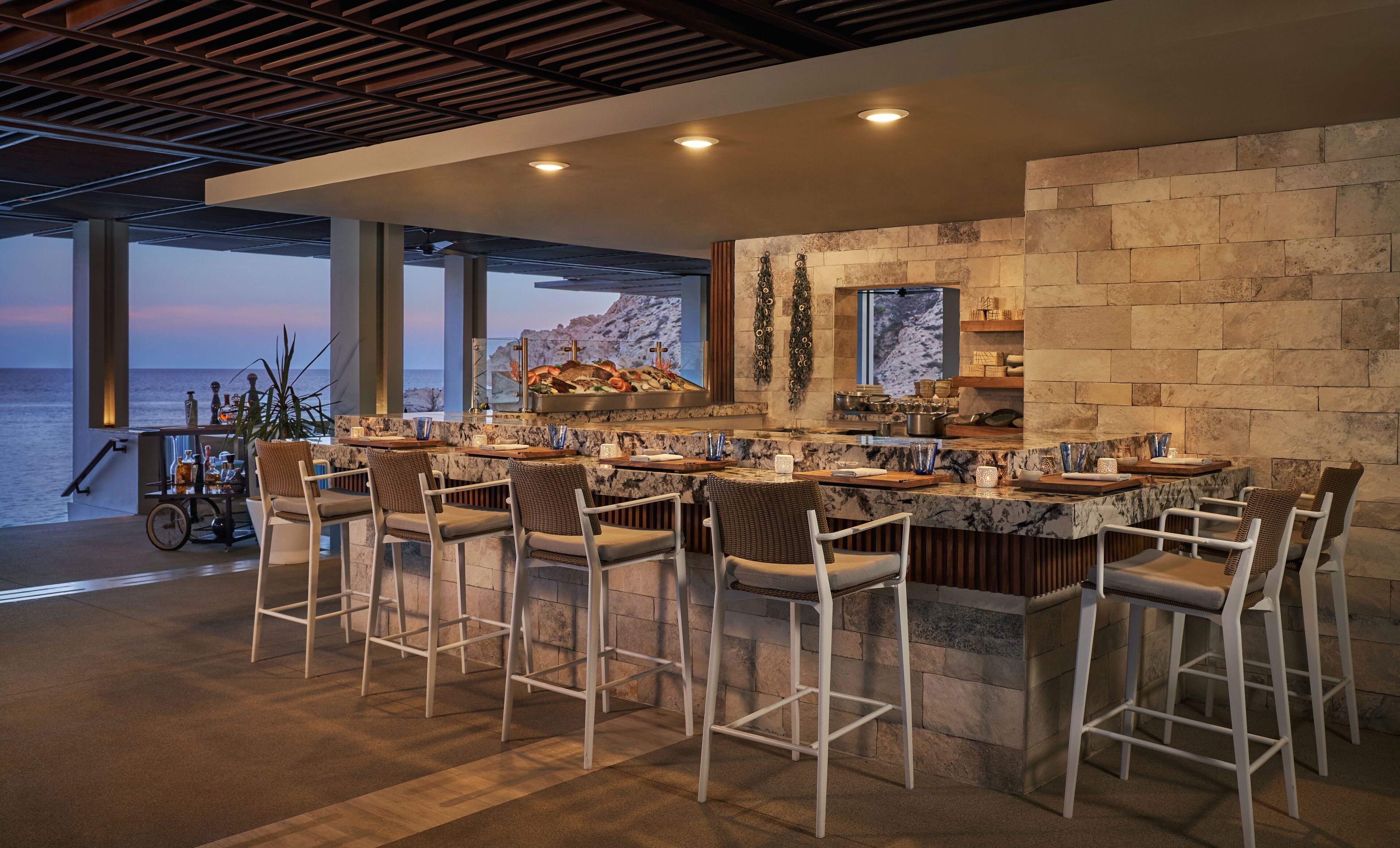 Uma cozinha moderna com uma ilha grande, banquetas e vista para o oceano.