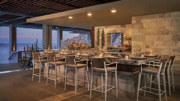 Uma cozinha moderna com uma ilha grande, banquetas e vista para o oceano.