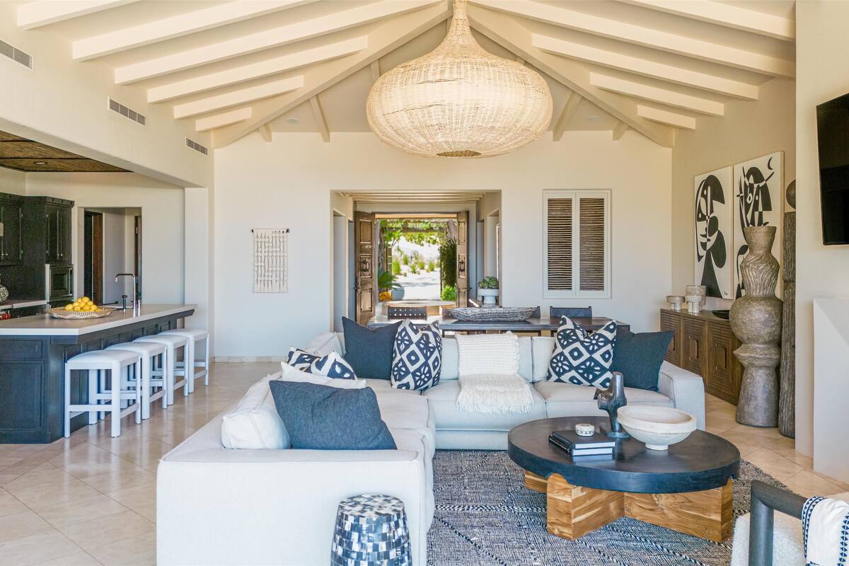 A spacious living area with a high ceiling, a dining area, and a kitchen.