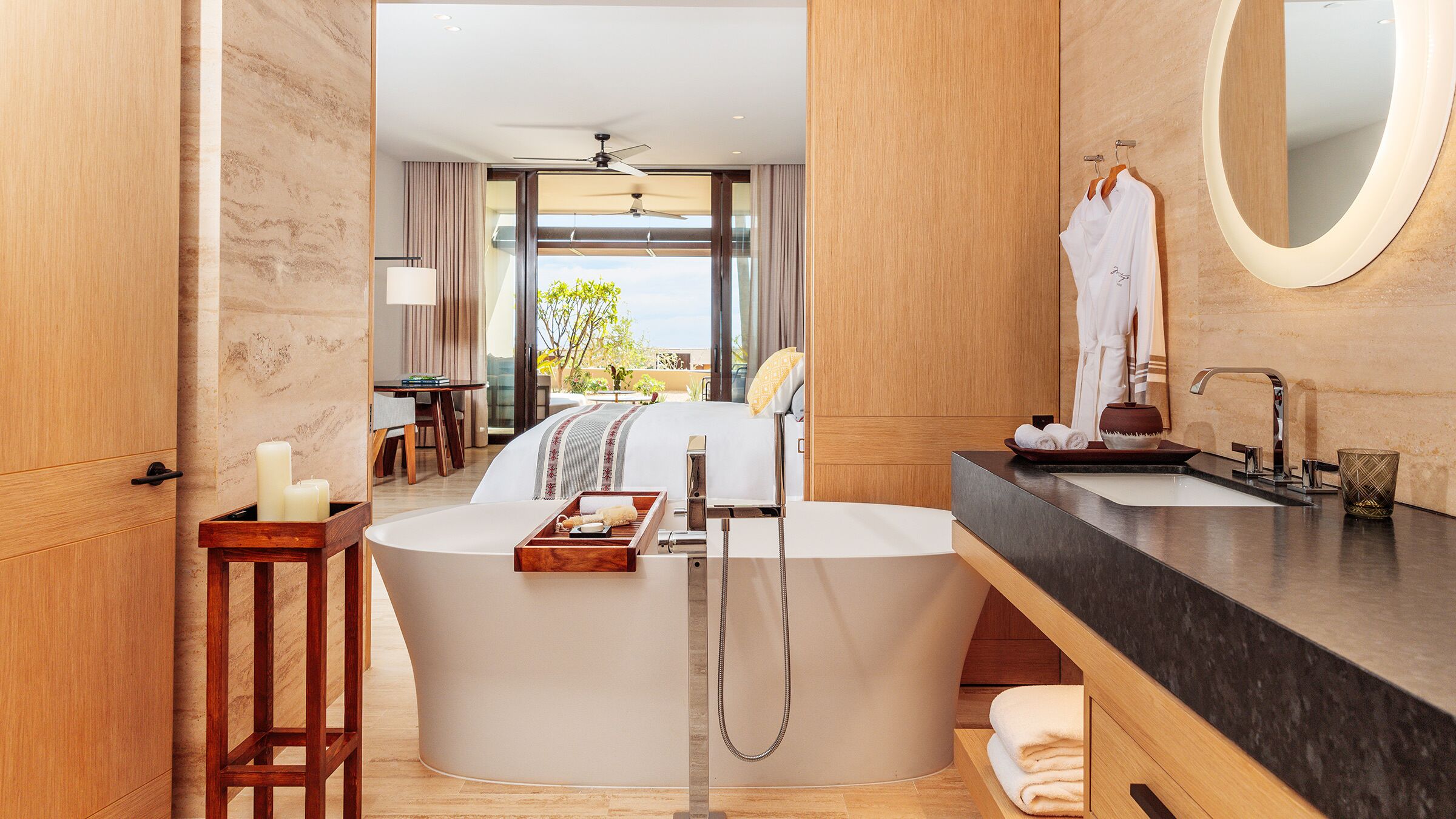 A modern bathroom with a bathtub, a vanity with a mirror, and a view of the outdoors.