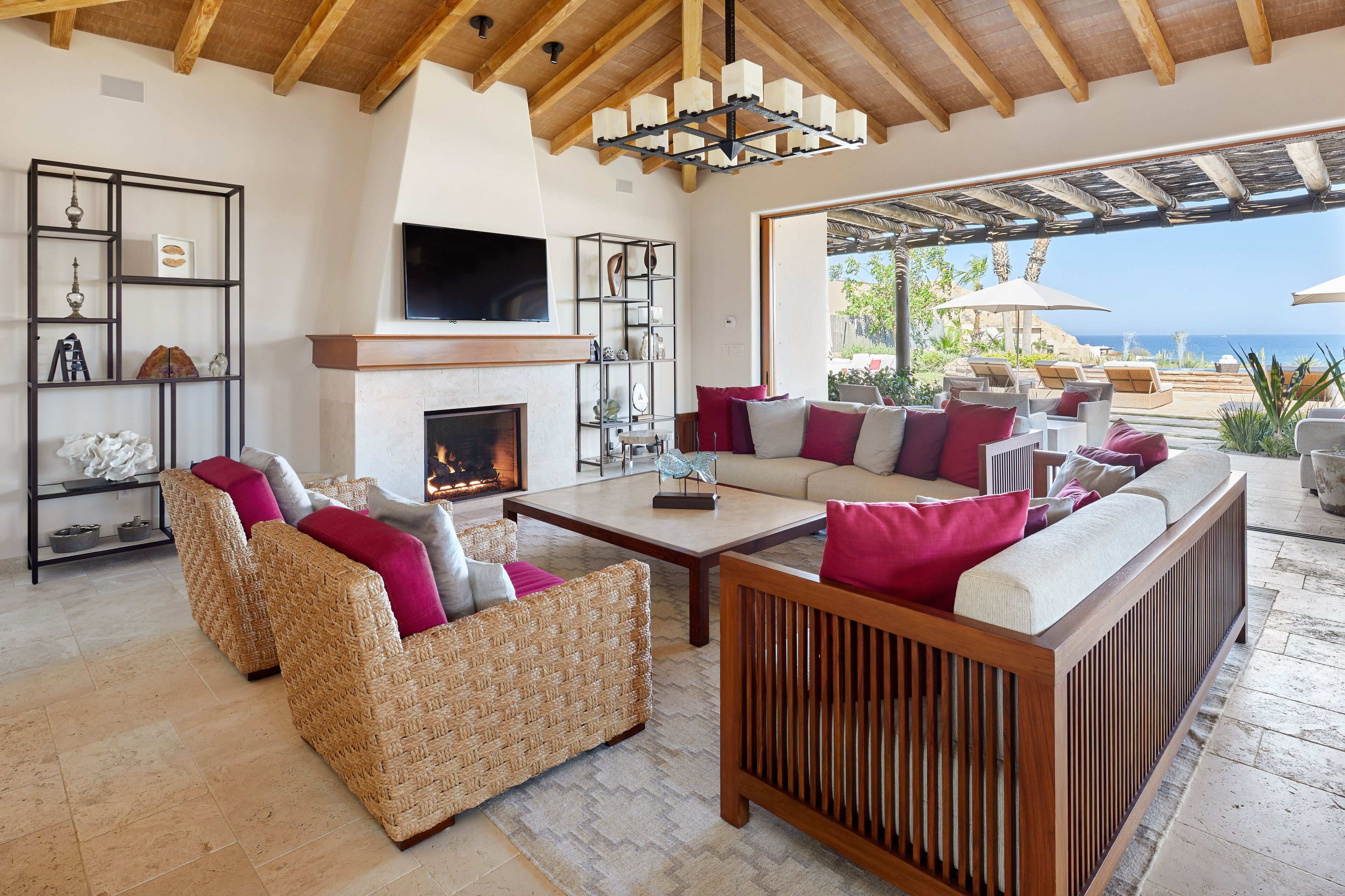 Amplia sala de estar con muebles de mimbre, chimenea y vista al océano.