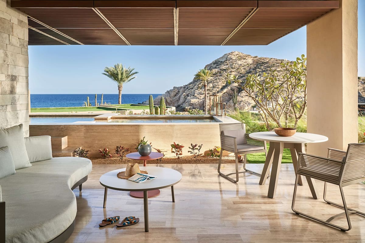 A modern outdoor seating area with a view of the ocean and a pool.