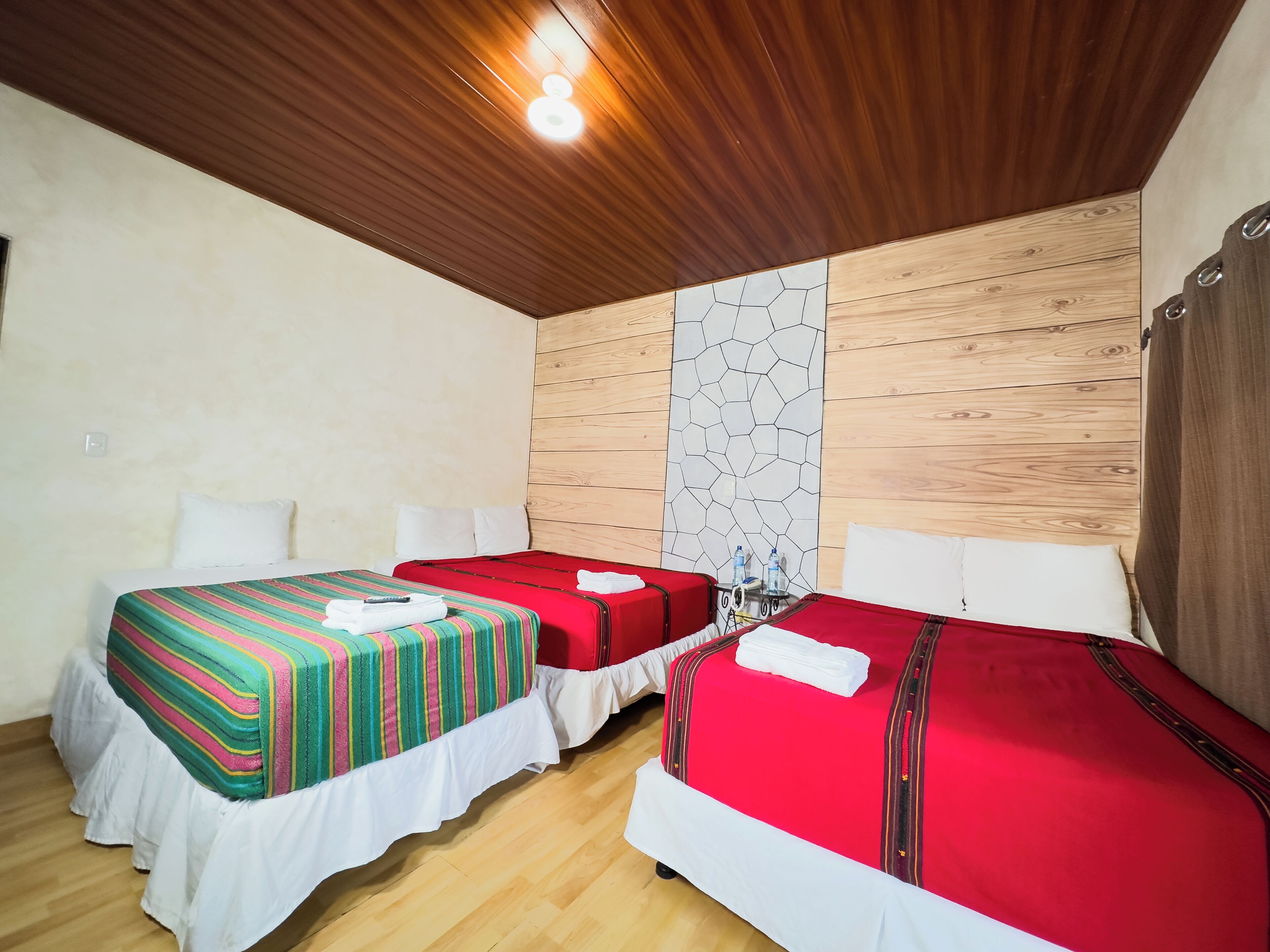 Une chambre d’hôtel avec deux lits, un plafond en bois et un mur orné d’un motif géométrique.