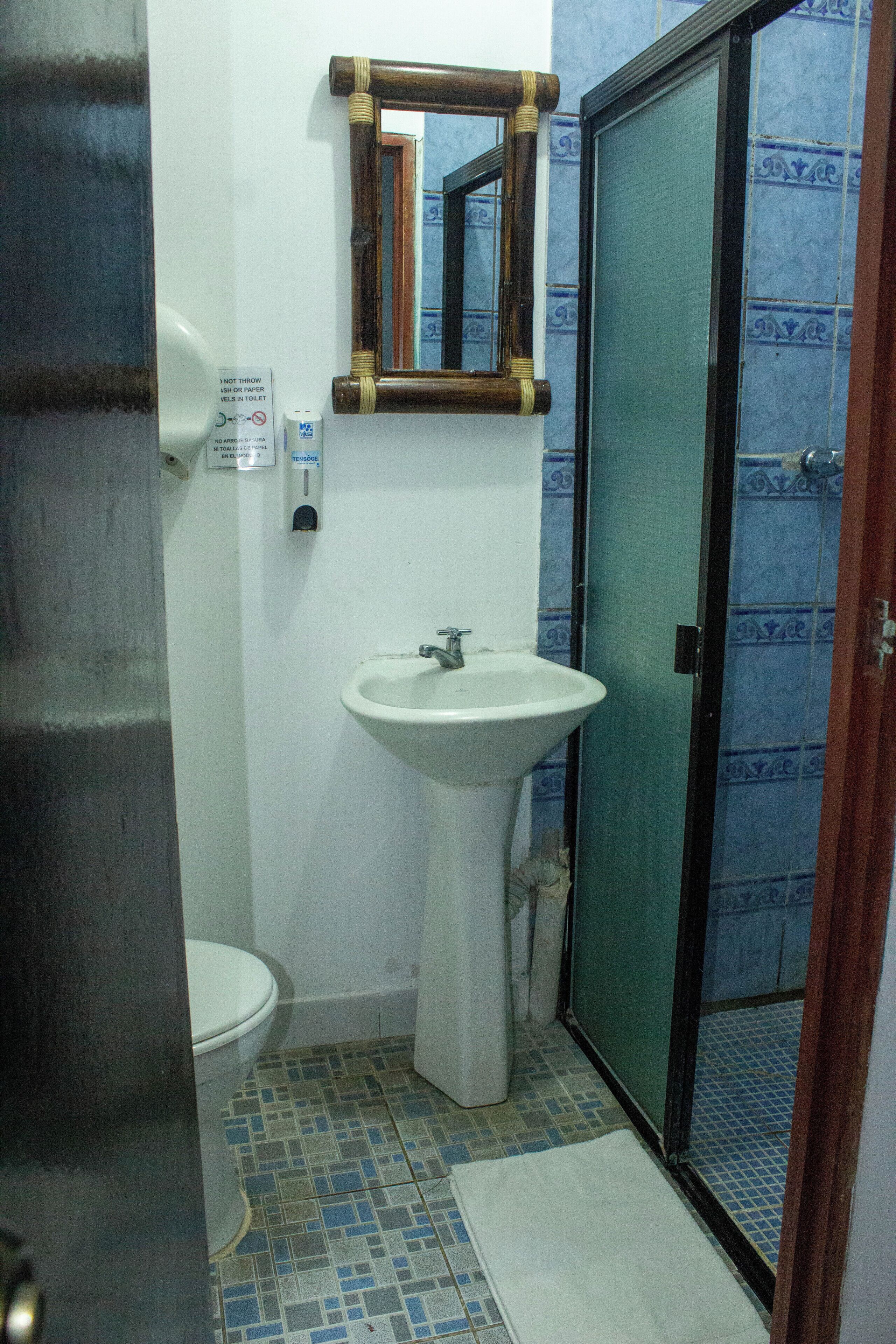 A bathroom with a toilet, sink, mirror, and shower door.
