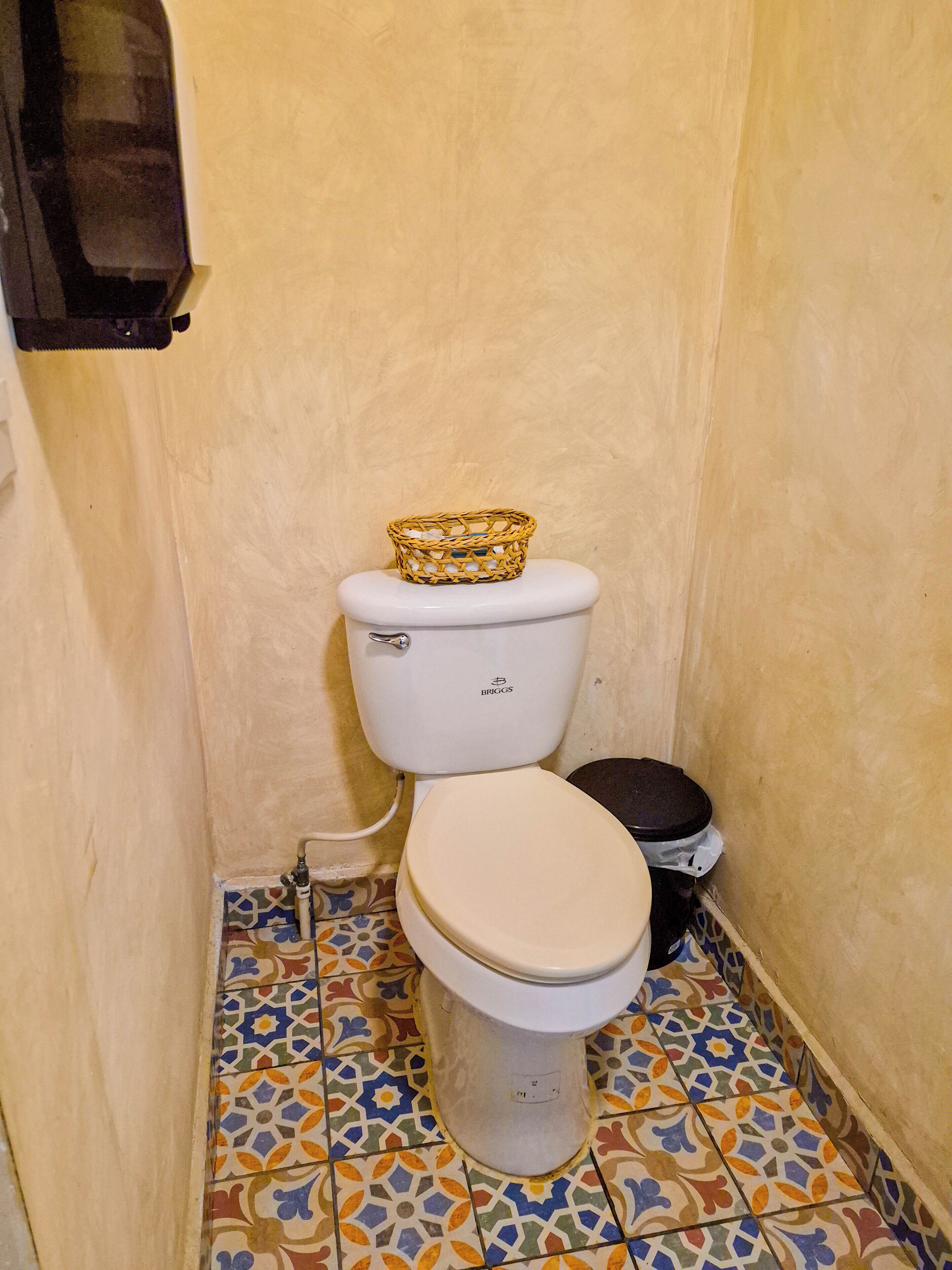 A small bathroom with a toilet, a bidet, and a trash bin.