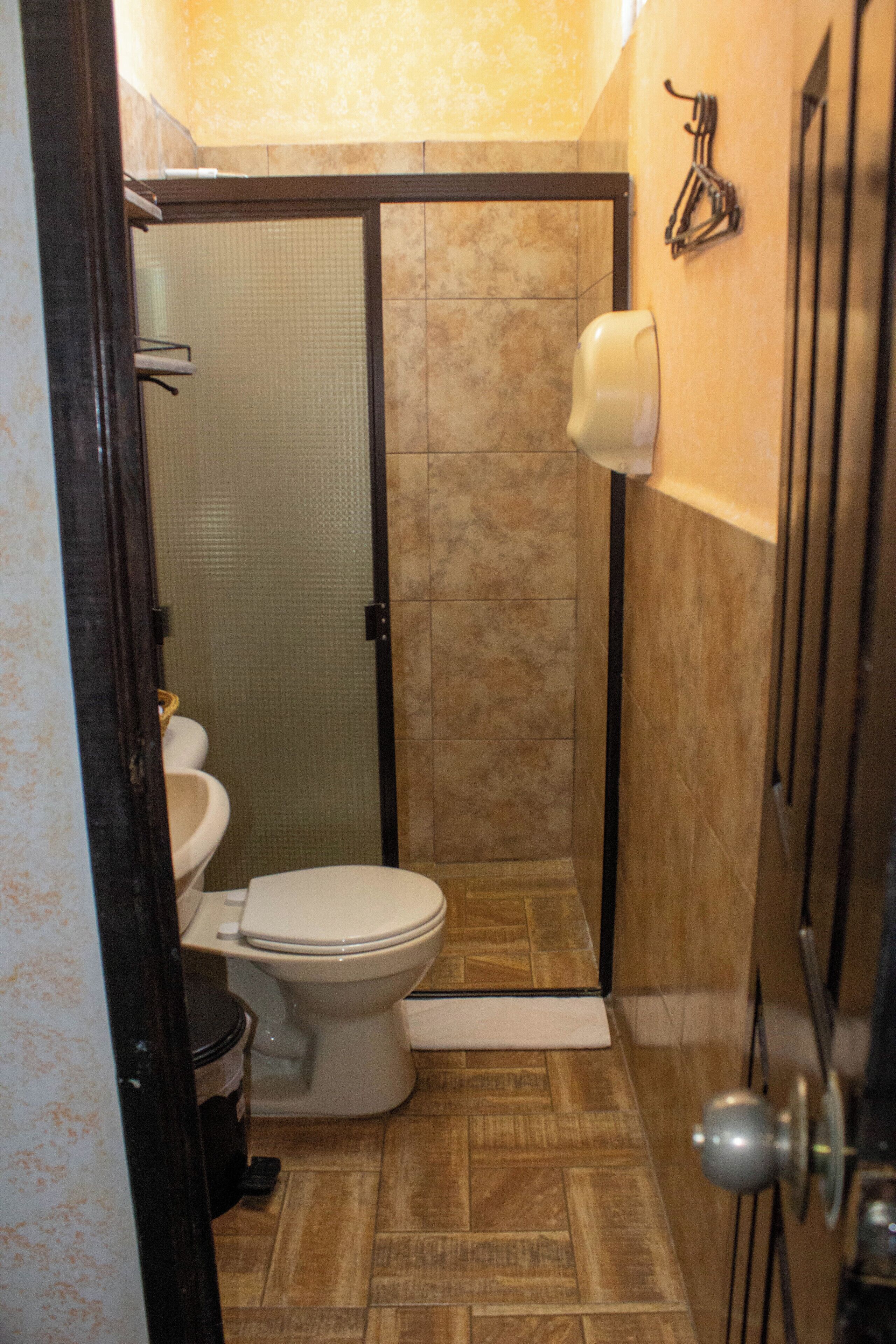 Ein Badezimmer mit Toilette, Duschkabine und Handtuchhalter.