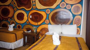 A hotel room with two beds, a wooden headboard, a small table with a vase of flowers, and a wall with a circular wood pattern.