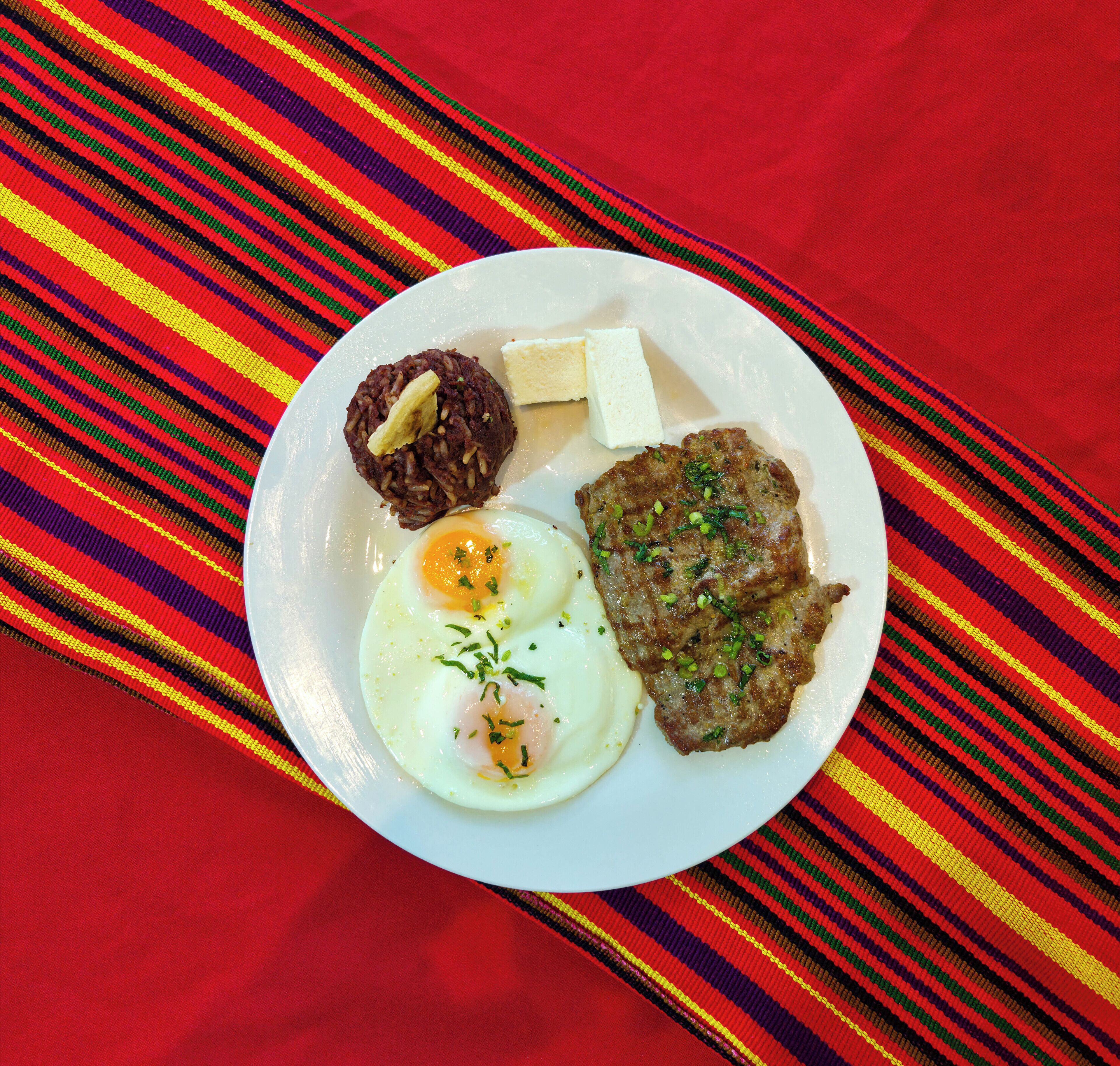 A plate with eggs, a piece of meat, and a small portion of rice.