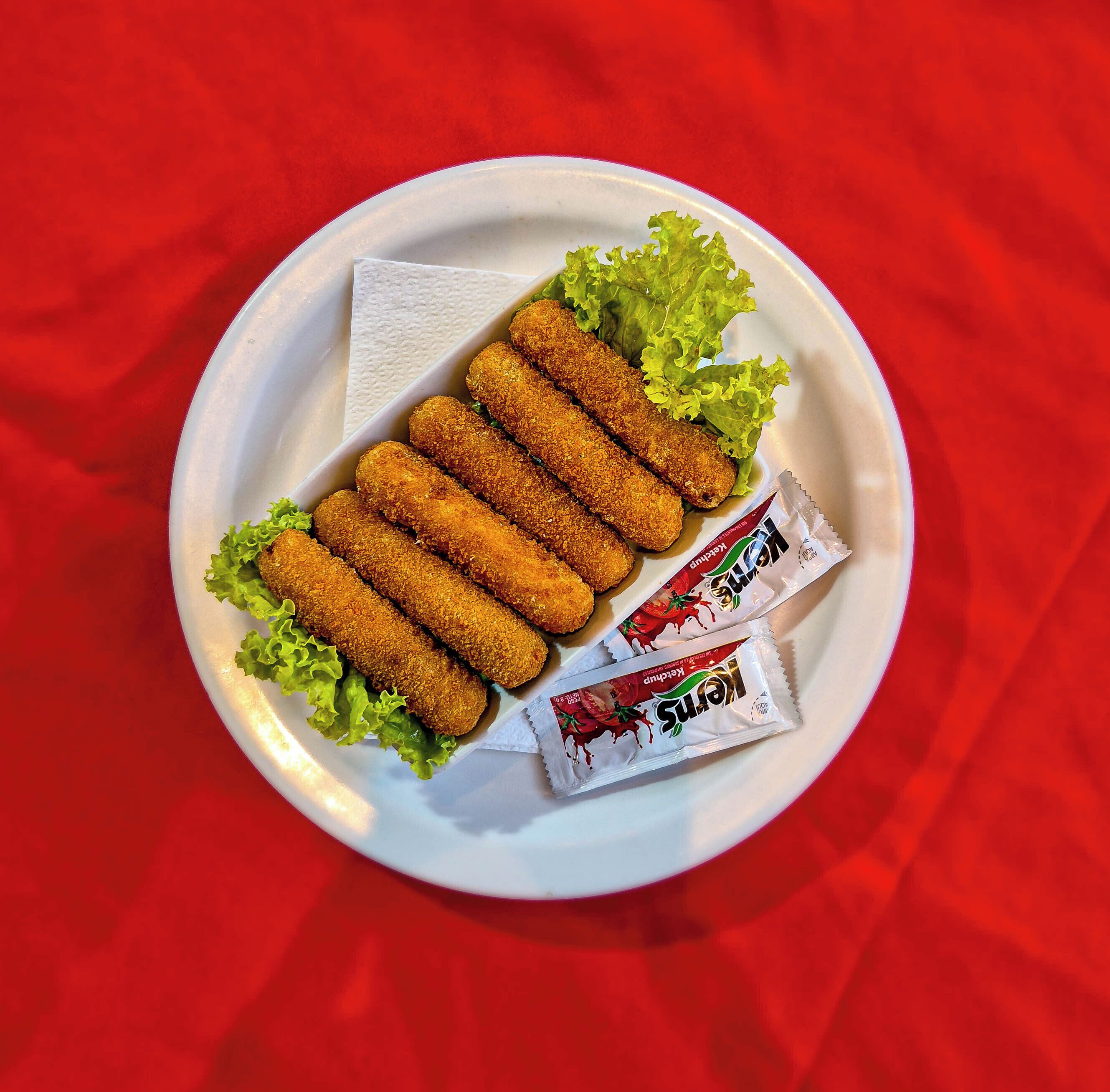 A plate with breaded food items and two packets of condiments.