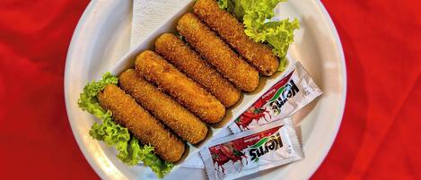 A plate with breaded food items and two packets of condiments.