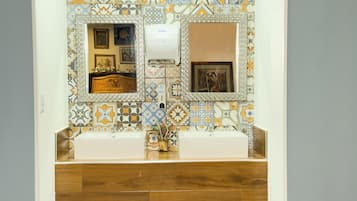 Une salle de bain avec deux lavabos, un miroir et un mur recouvert de carreaux décoratifs.
