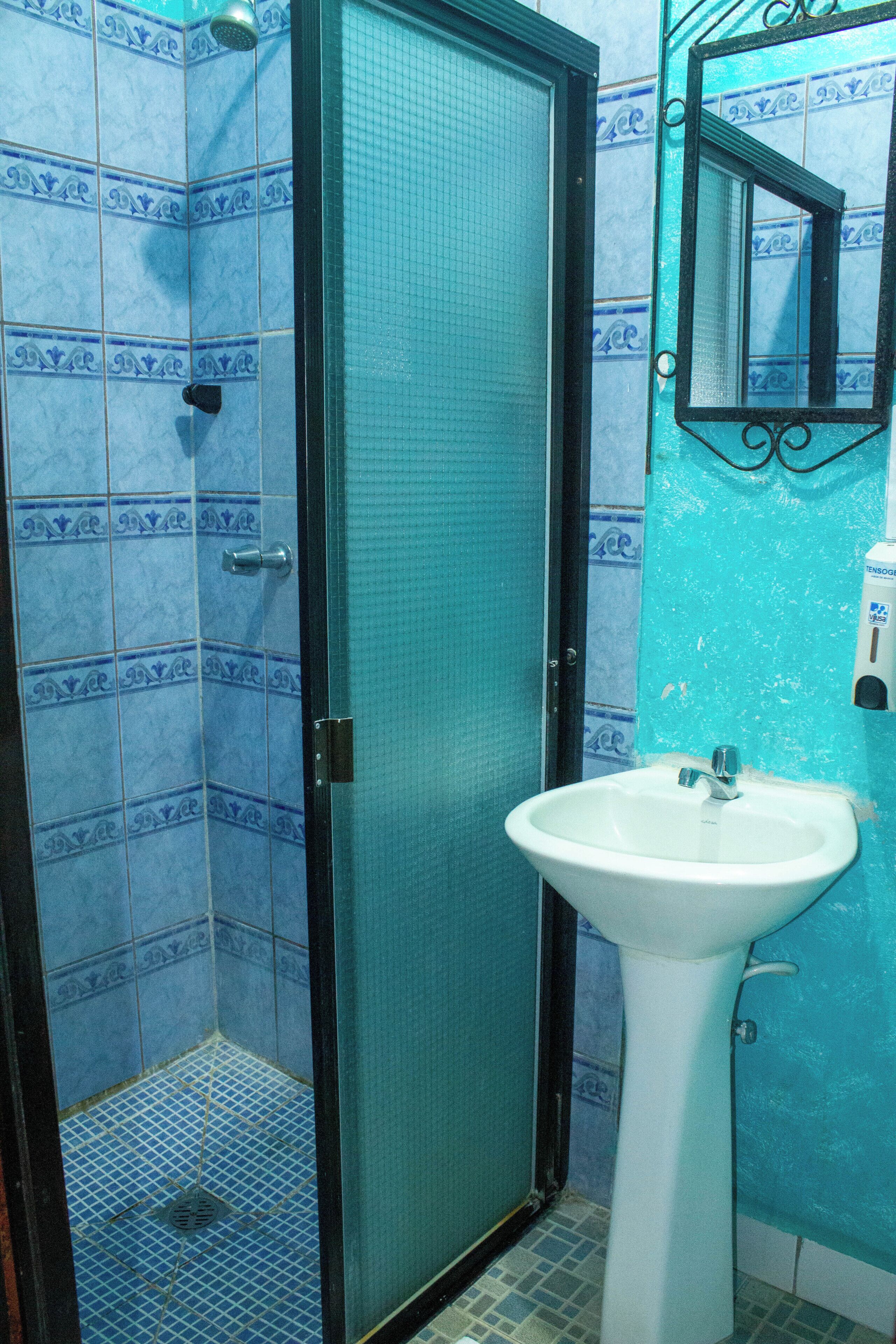 A bathroom with a shower, a sink, and a mirror.