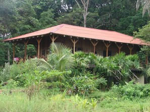 A wooden structure with a red roof surrounded by lush greenery. - Casa Grande Ecolodge at Pacuare Reserve (Matina)
