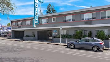 A motel with a prominent neon sign, a parking lot, and a car parked in front.