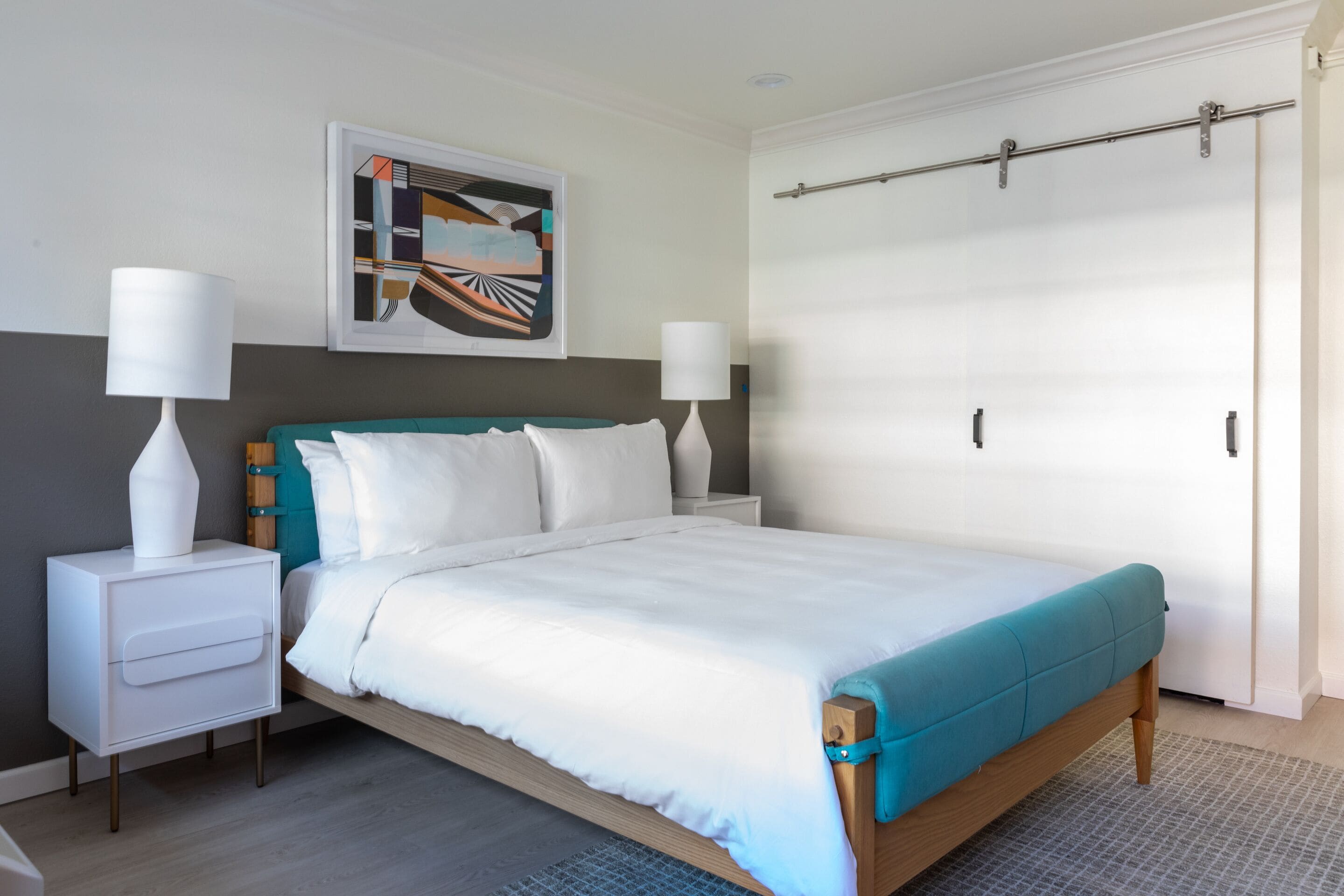 A modern bedroom with a bed, nightstands, a wardrobe, and a painting on the wall.