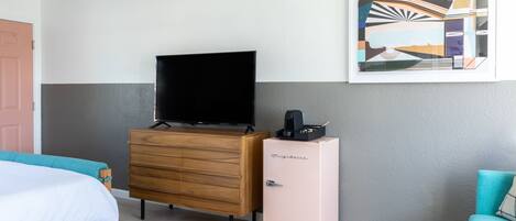 Une chambre d’hôtel avec un lit, une commode, une télévision, un réfrigérateur et un tableau au mur.