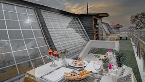 A dining area with a table set for two, featuring a meal, drinks, and decorative items. - Rose Petal (Srinagar)