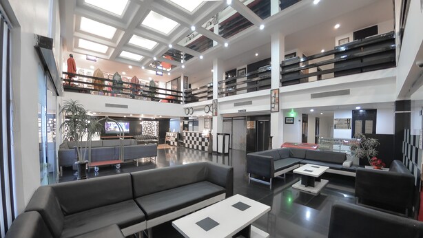 A spacious lobby with a modern design, featuring a large seating area, a checkered floor, and a second-floor balcony with a railing. - Rose Petal (Srinagar)