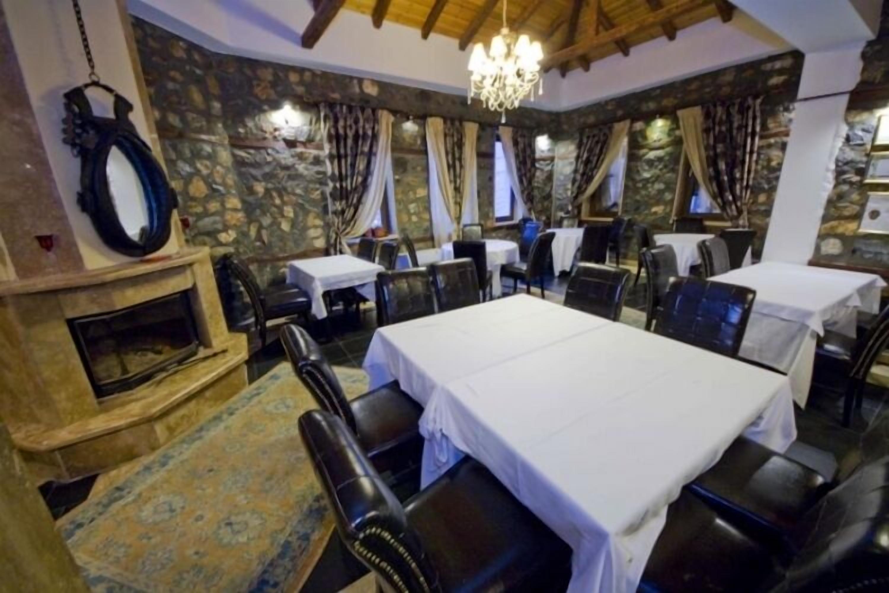 A restaurant with stone walls, a fireplace, and multiple tables and chairs.