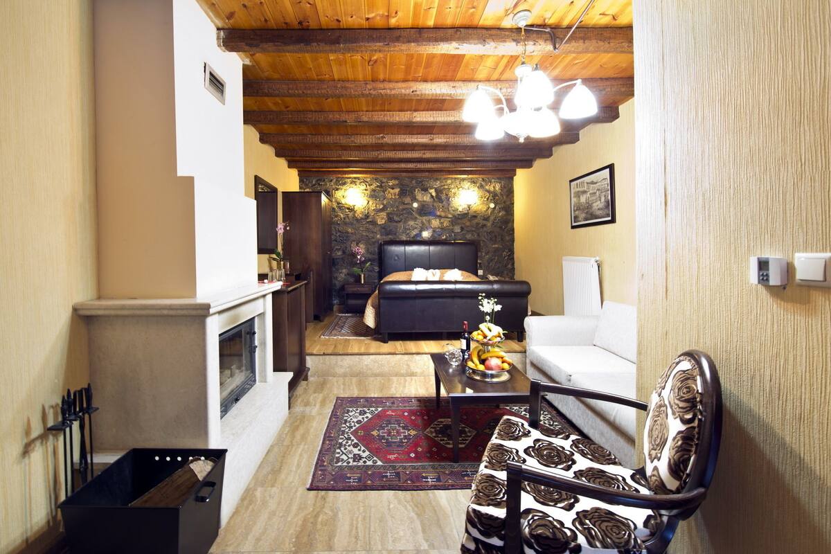 A cozy living room with a fireplace, a sofa, a coffee table, and a patterned armchair.