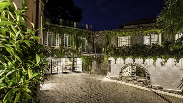 A courtyard with a cobblestone floor, a stone archway, and a gate. - Villa Liberty - Lake Como Rooms & SPA (Como)