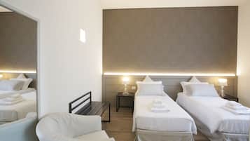 A hotel room with two single beds, a bench, a chair, and a large mirror.