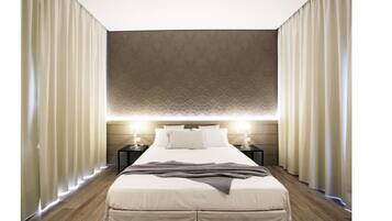 Una habitación de hotel moderna con una cama grande, lámparas de noche y un cabecero estampado.