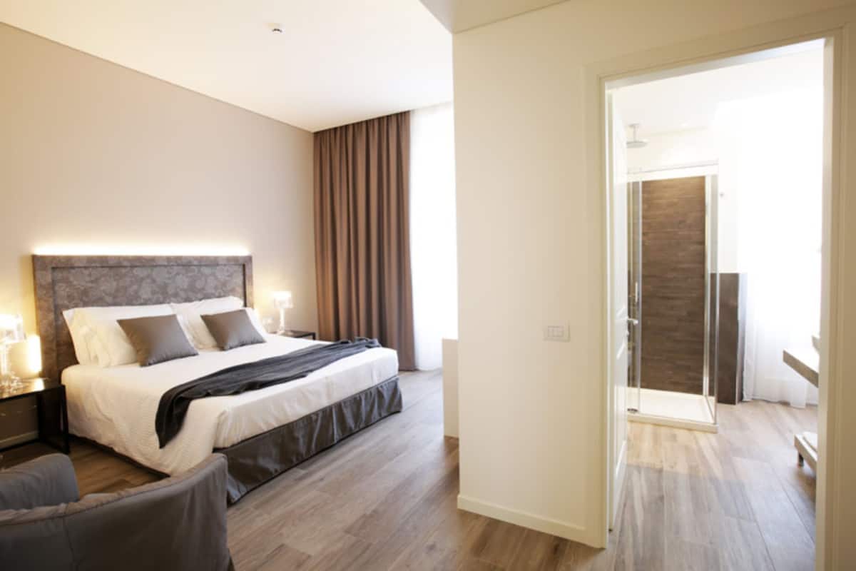 A modern bedroom with a large bed, bedside tables, and a view of a bathroom through an open door.