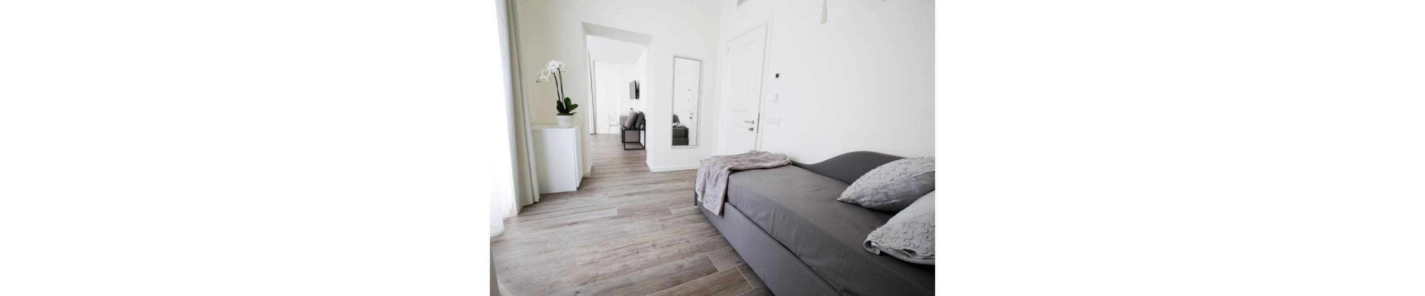 Un salón moderno y minimalista con un sofá gris y una mesita auxiliar blanca.