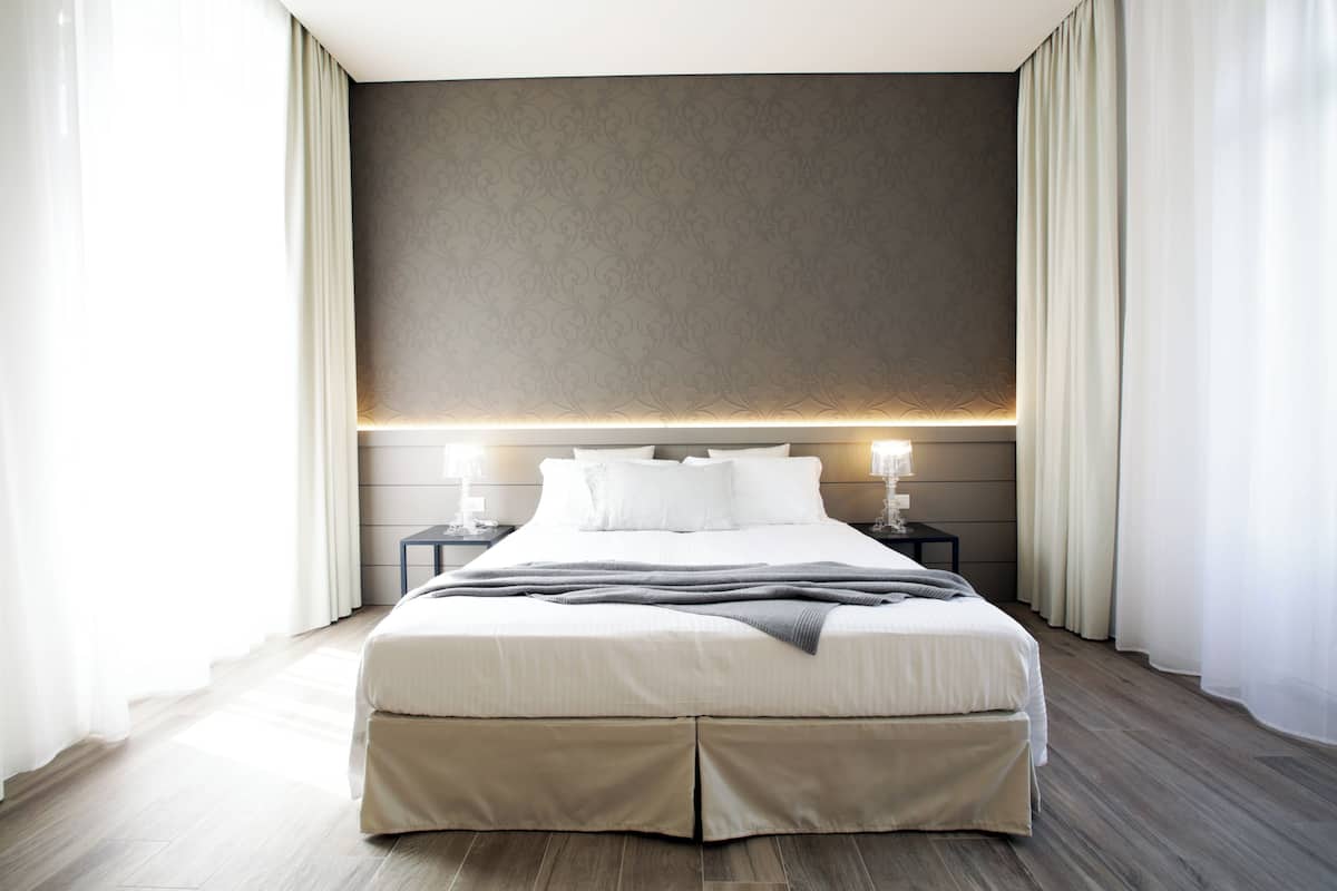 A modern hotel room with a large bed, bedside tables, and a neutral color scheme.