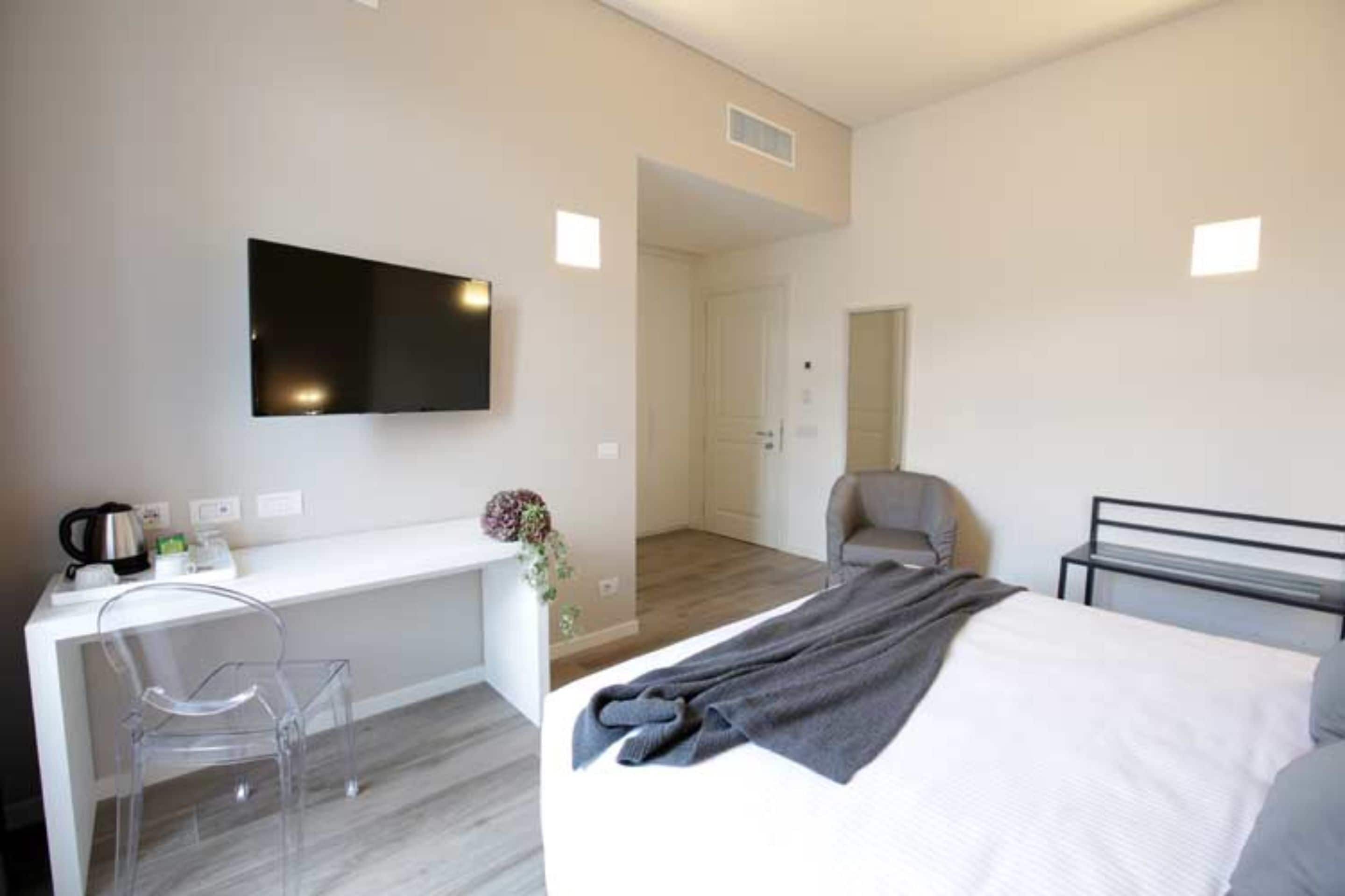 Una habitación de hotel moderna con una cama, un escritorio, una silla y un televisor.