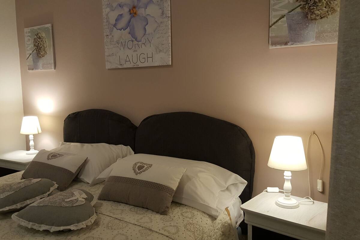 A neatly made bed with a dark headboard, two bedside tables with lamps, and decorative pillows.