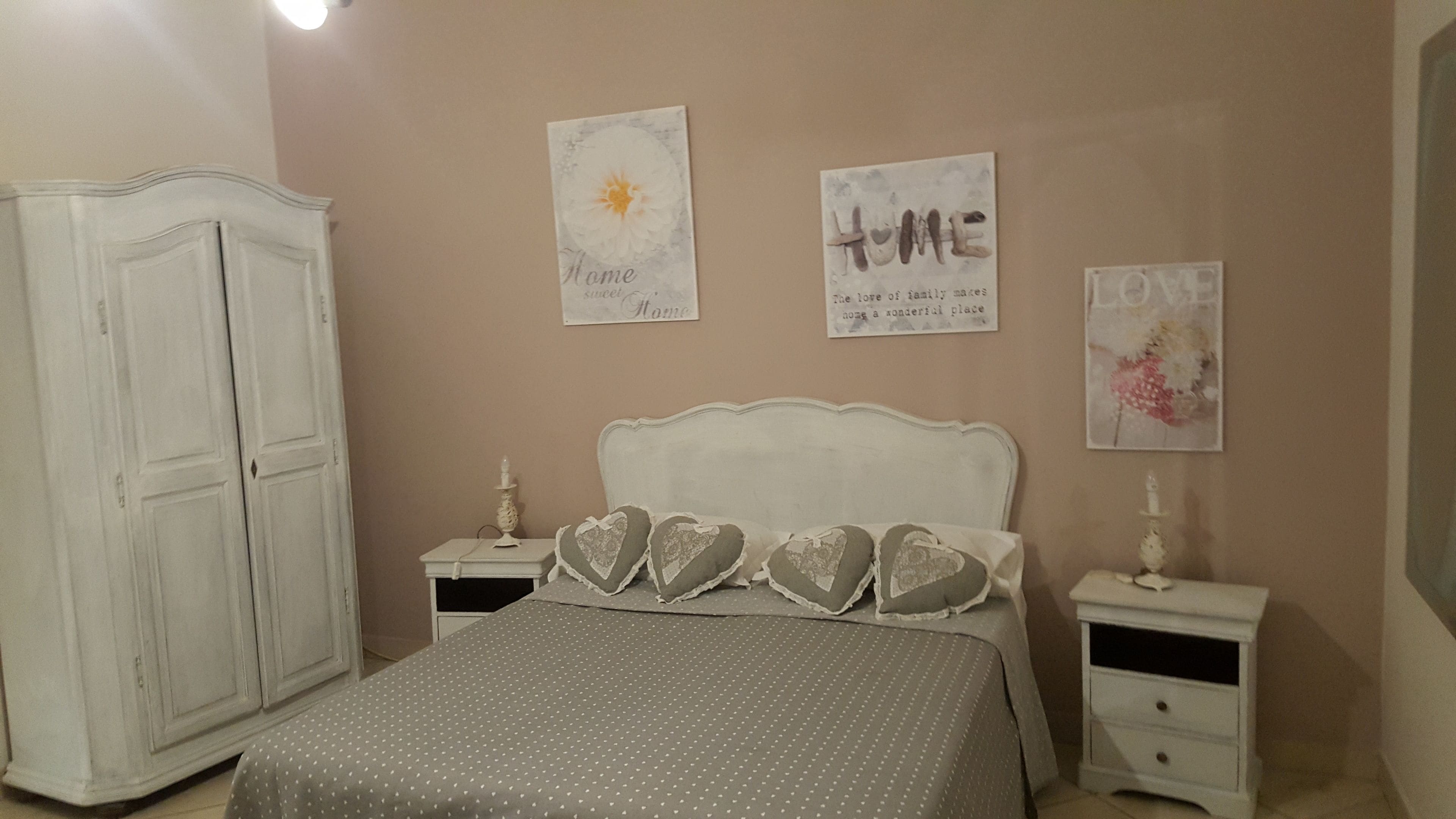 Un dormitorio con cama, dos mesitas de noche, un armario y tres cuadros.