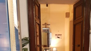 A hallway with wooden doors, a tiled floor, a small rug, a mirror, and a sign on the wall. - B&B Napoli Centro (Naples)