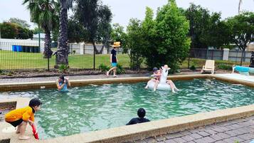 Zona de piscina con borde de azulejos, solárium de hormigón y una valla al fondo.