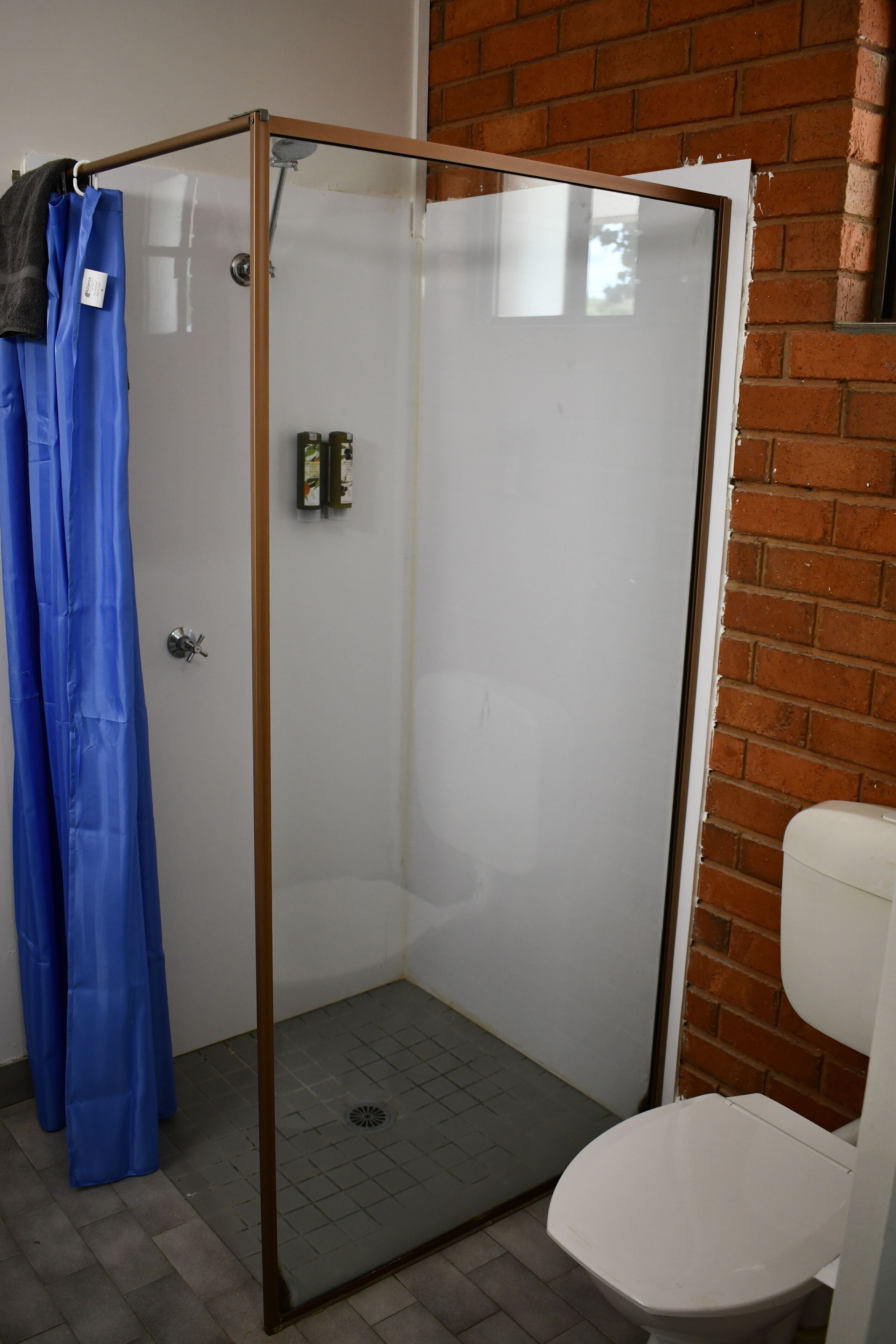Cabina de bany amb vidre i un vàter blanc a prop.