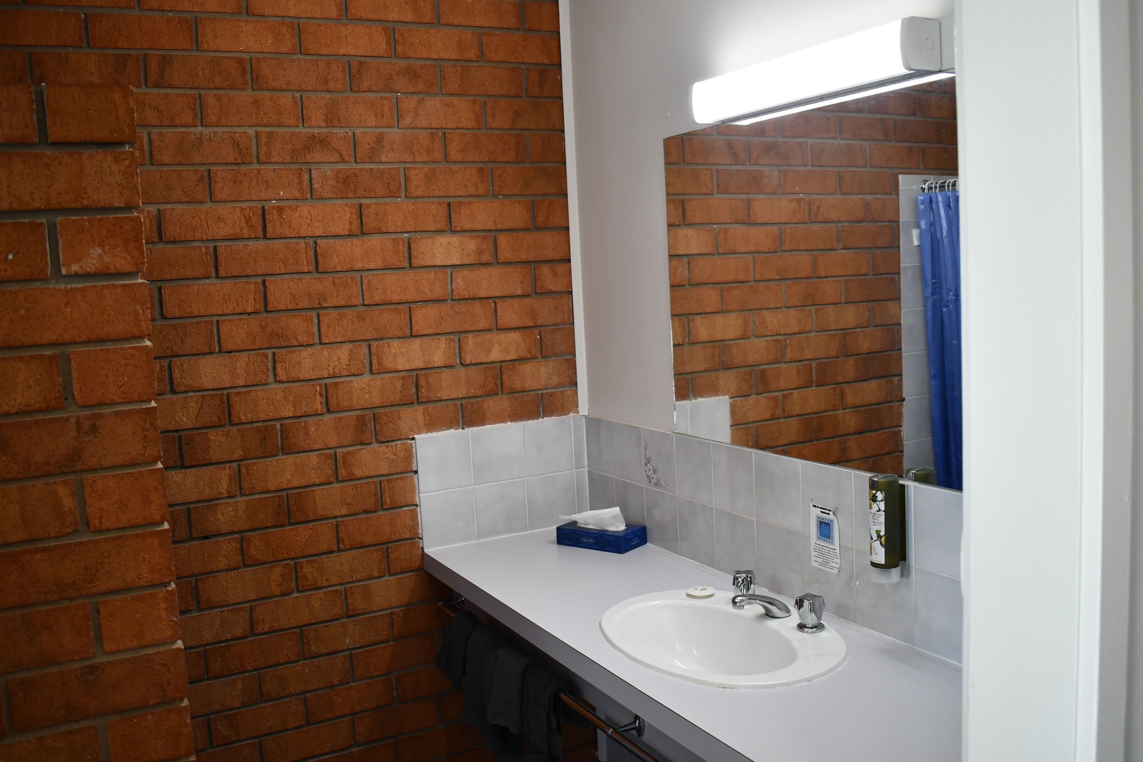A bathroom with a white sink, a mirror, and a blue shower curtain.