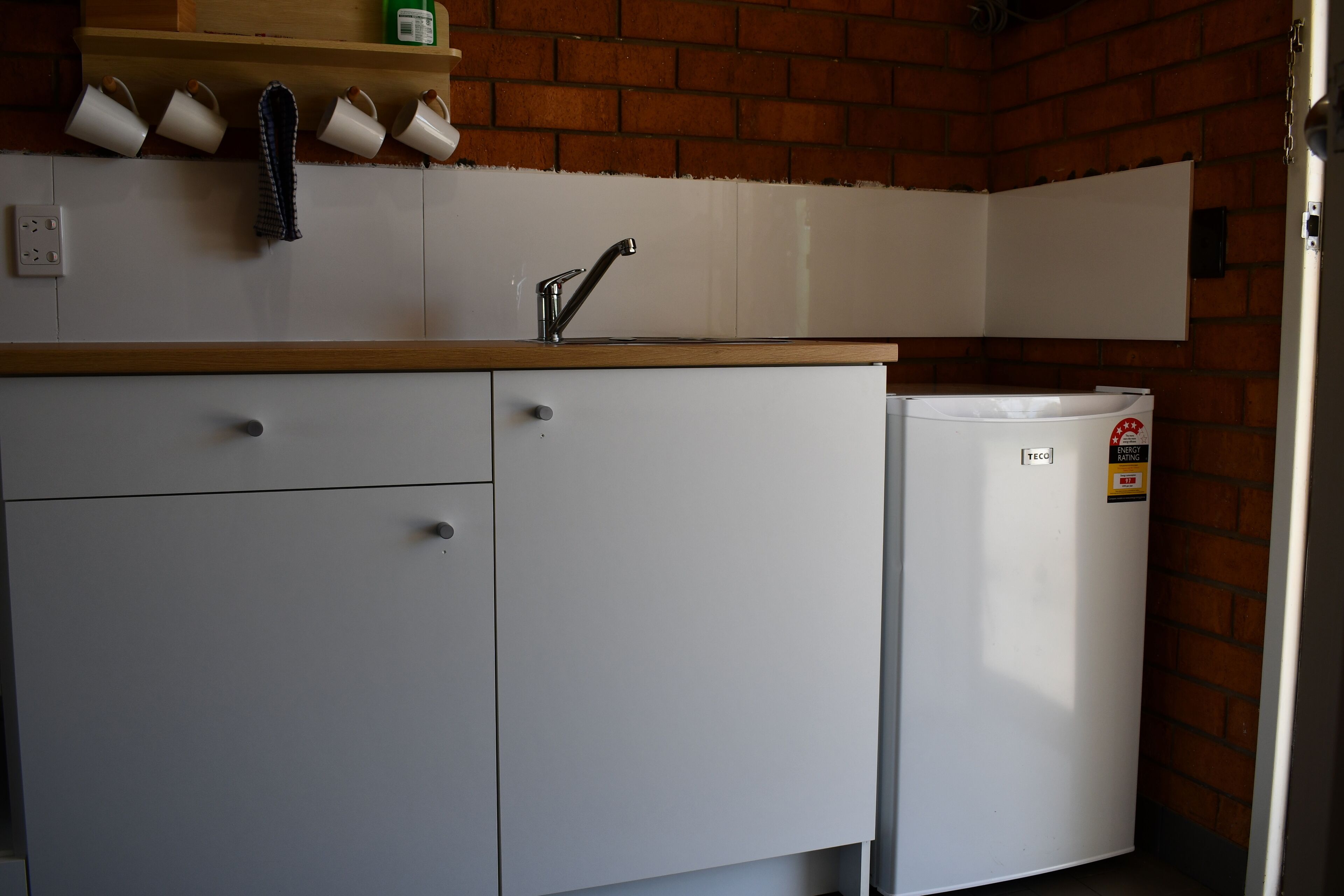 A kitchen with white cabinets, a sink, and a refrigerator.