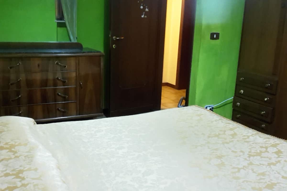 Une pièce comprenant un lit, une commode et une porte donnant sur une autre pièce.
