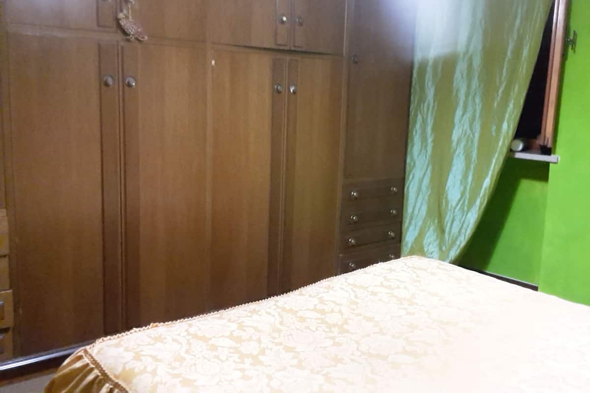 Une chambre à coucher avec un lit, une armoire en bois et un mur vert.