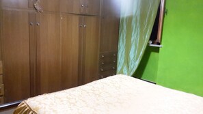 Un dormitorio con cama, un armario de madera y una pared verde.