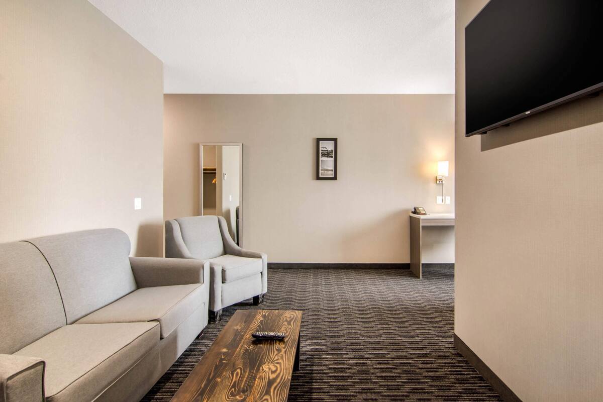 A hotel room with a sofa, armchair, and a wooden coffee table.