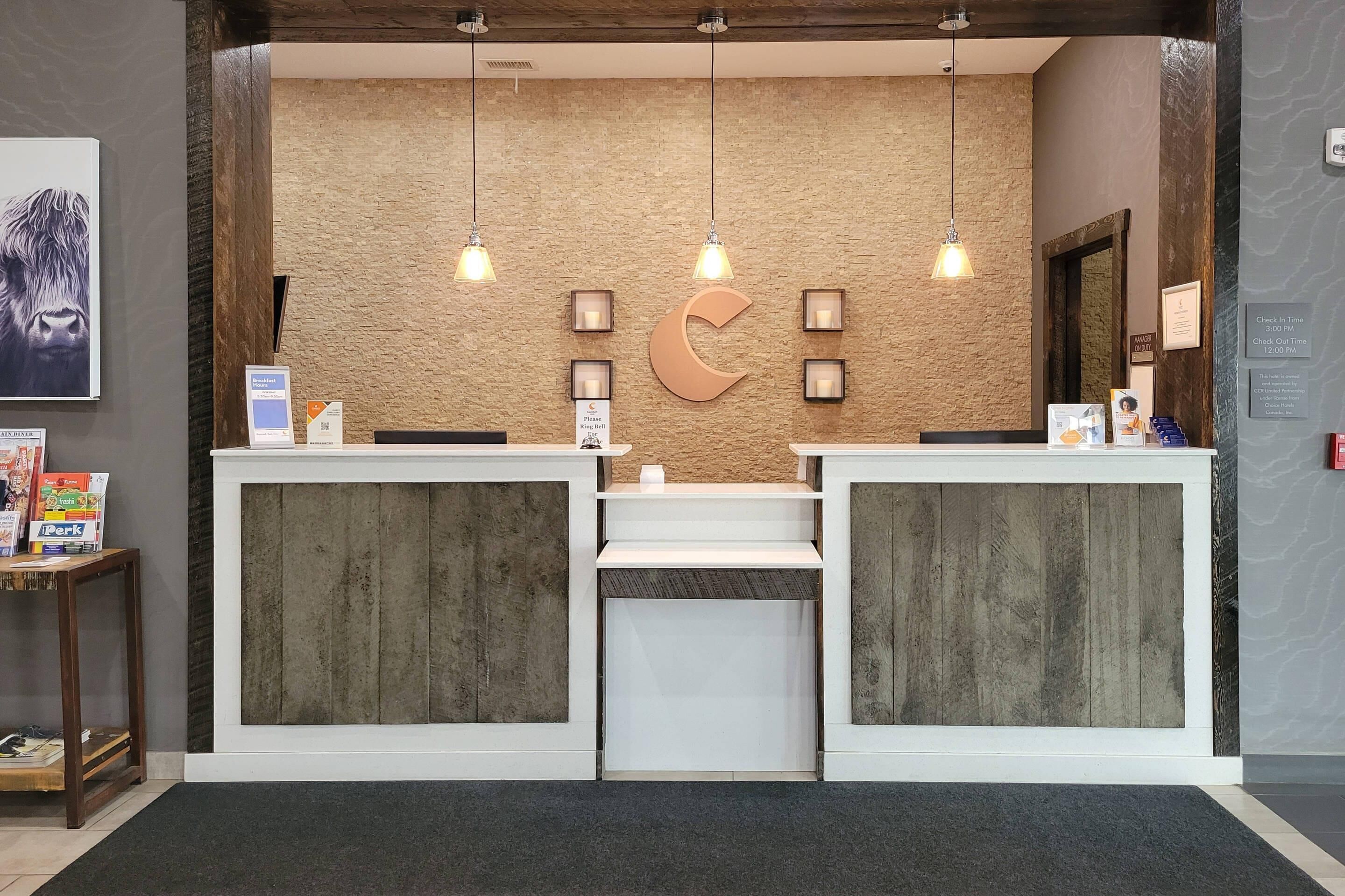 A reception desk with a wooden backdrop, a large crescent moon decoration, and pendant lighting.