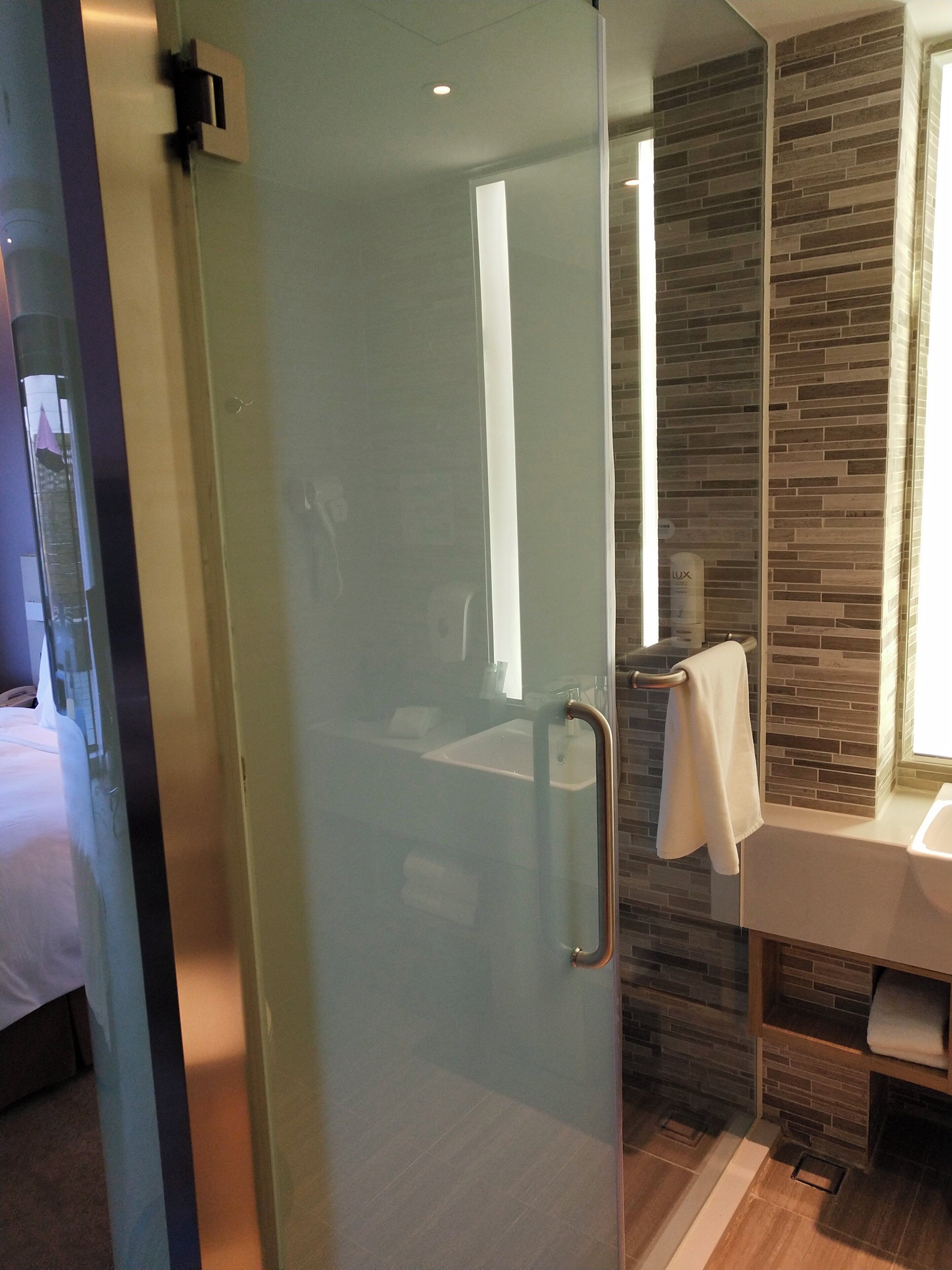 A modern bathroom with a glass shower enclosure, a visible towel rack, and a sink with a mirror.